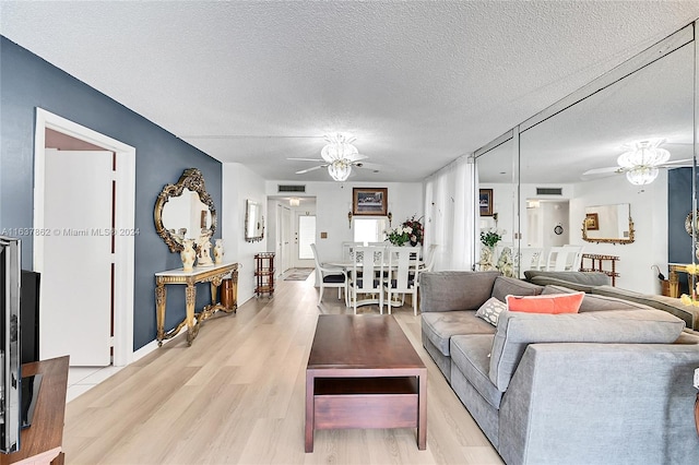 living room with ceiling fan, a textured ceiling, and light hardwood / wood-style flooring