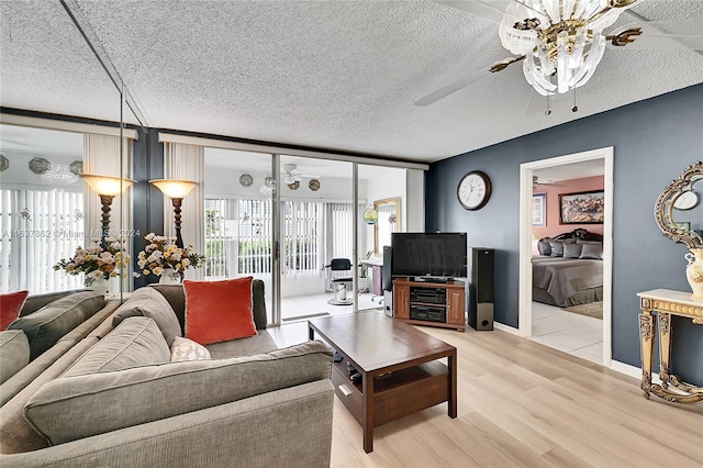 living room featuring ceiling fan, hardwood / wood-style flooring, and a textured ceiling