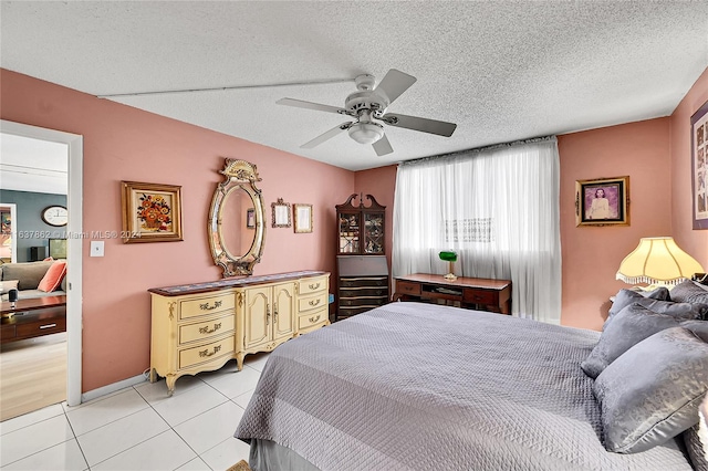 bedroom with a textured ceiling, light tile patterned floors, and ceiling fan