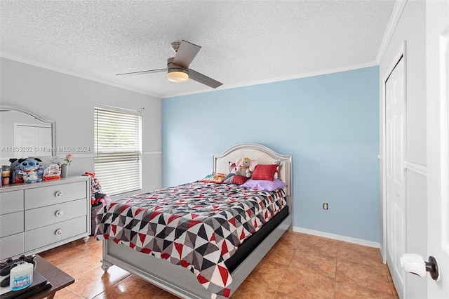 tiled bedroom featuring a textured ceiling, ornamental molding, a closet, and ceiling fan