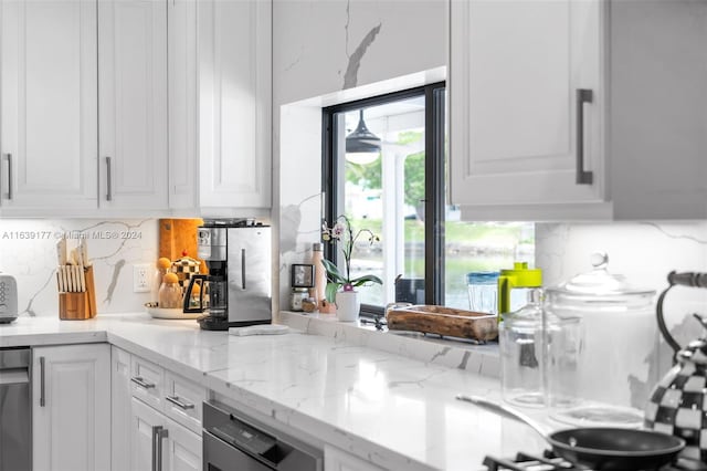 kitchen with white cabinetry, backsplash, and light stone counters