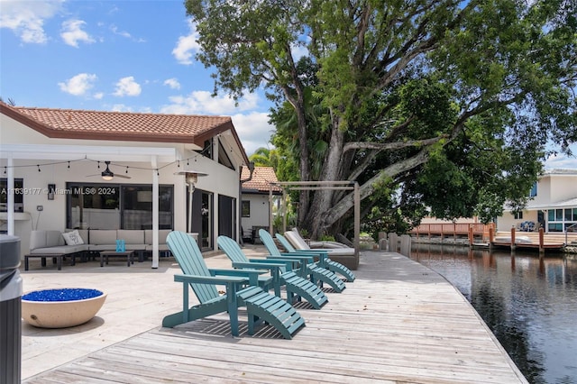 rear view of house featuring a deck with water view, outdoor lounge area, and ceiling fan