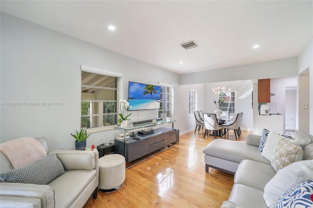 living room featuring light wood-type flooring and a notable chandelier