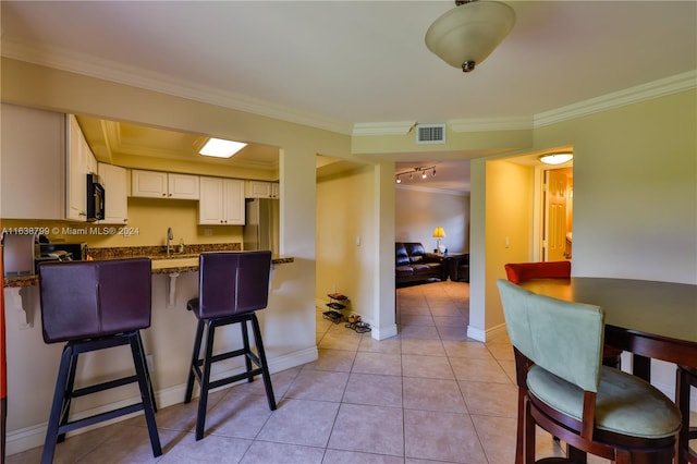 kitchen with stainless steel fridge, light tile patterned flooring, white cabinets, and crown molding