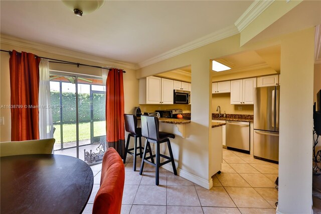 kitchen featuring stainless steel appliances, a breakfast bar, white cabinetry, and light tile patterned floors