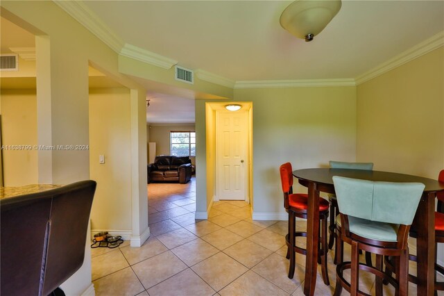 dining space featuring light tile patterned floors, baseboards, visible vents, and crown molding