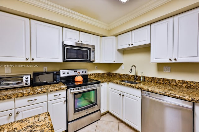 kitchen with appliances with stainless steel finishes, white cabinets, dark stone countertops, ornamental molding, and sink