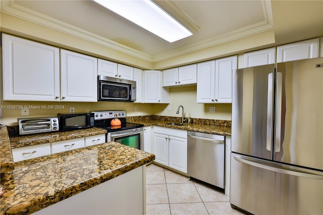 kitchen featuring light tile patterned flooring, appliances with stainless steel finishes, white cabinets, dark stone counters, and sink