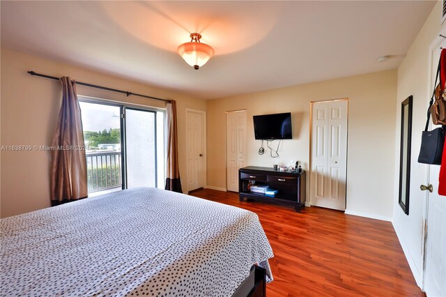 bedroom featuring visible vents, baseboards, dark wood-type flooring, access to exterior, and multiple closets