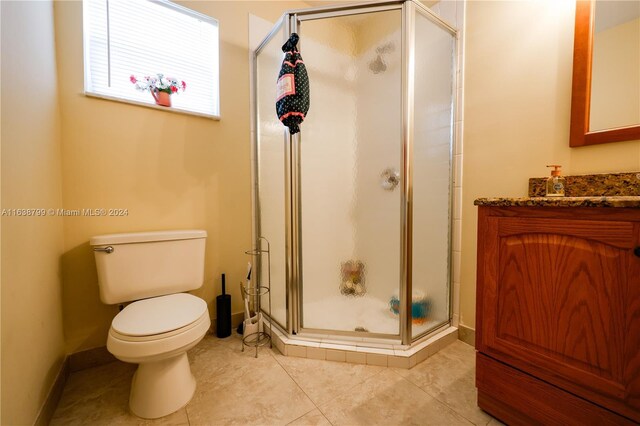 full bath featuring toilet, a shower stall, vanity, and tile patterned floors