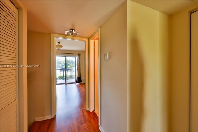 corridor featuring dark wood-style floors and baseboards