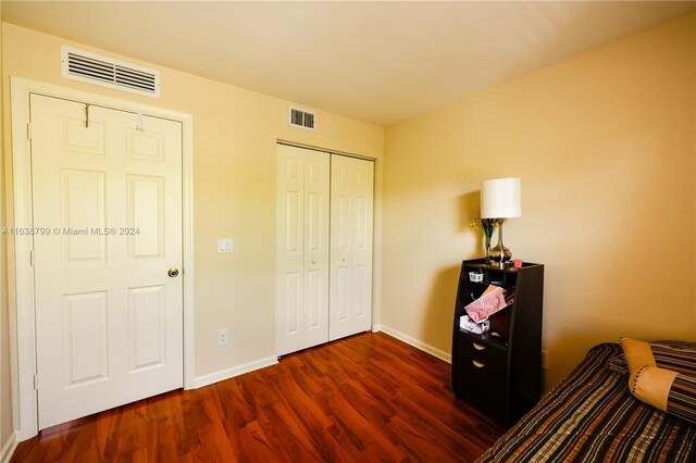 bedroom featuring a closet, dark wood finished floors, visible vents, and baseboards