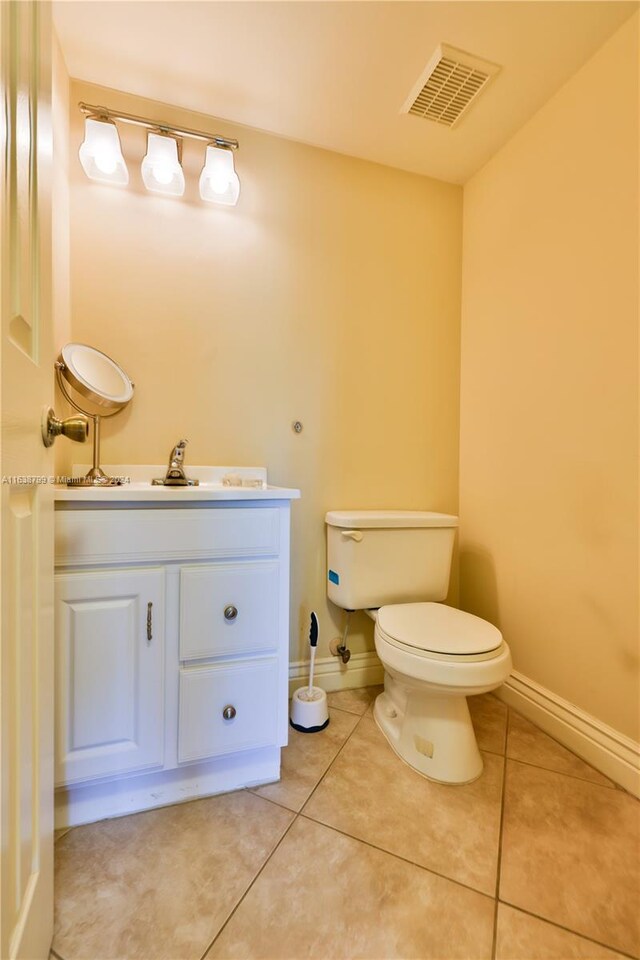 half bathroom with tile patterned flooring, toilet, vanity, visible vents, and baseboards