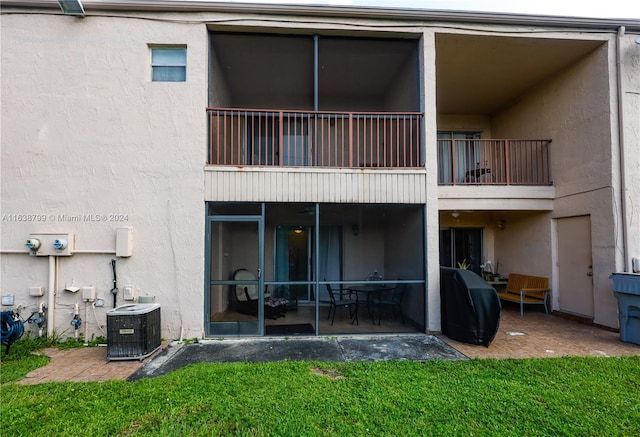 back of house with a balcony, central air condition unit, a patio, and a yard