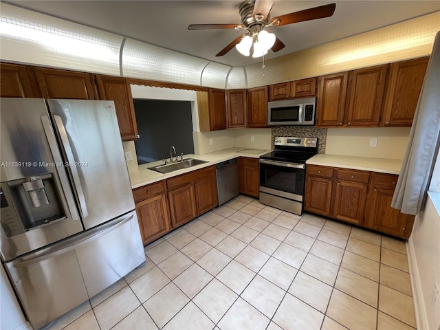 kitchen featuring tasteful backsplash, light tile patterned floors, stainless steel appliances, ceiling fan, and sink