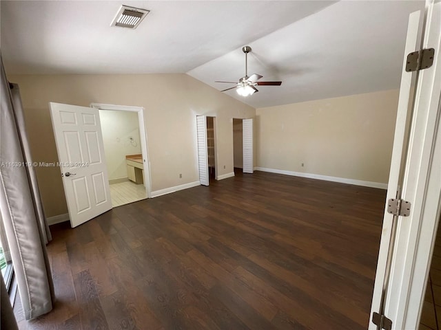 unfurnished bedroom with lofted ceiling, dark tile patterned flooring, ensuite bath, and ceiling fan