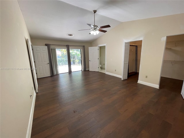 unfurnished bedroom with dark hardwood / wood-style floors, vaulted ceiling, ceiling fan, a closet, and a walk in closet