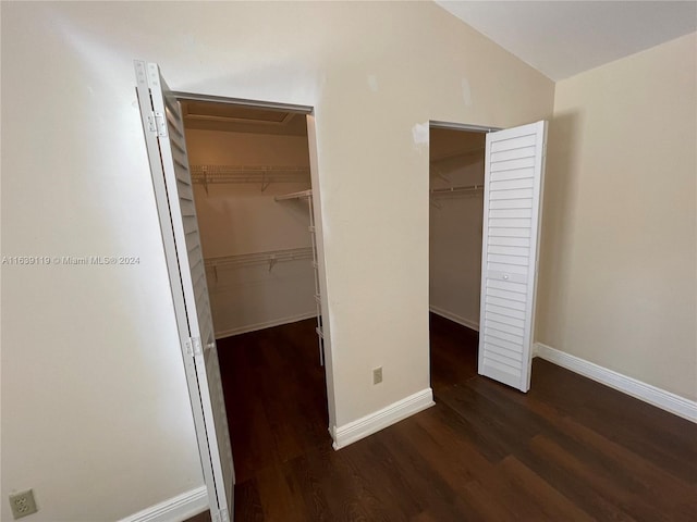 unfurnished bedroom featuring a spacious closet, hardwood / wood-style flooring, vaulted ceiling, and a closet