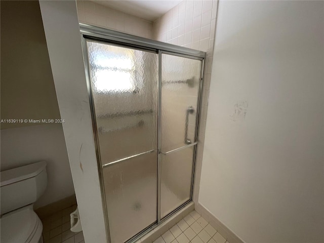 bathroom featuring an enclosed shower, toilet, and tile patterned flooring