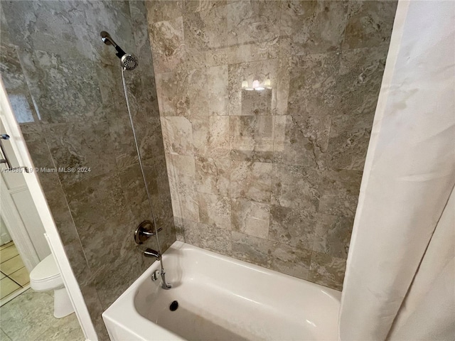 bathroom with tile patterned floors, tiled shower / bath, and toilet