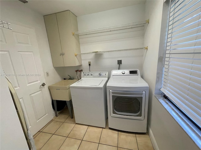 washroom featuring cabinets, washing machine and dryer, and light tile patterned flooring