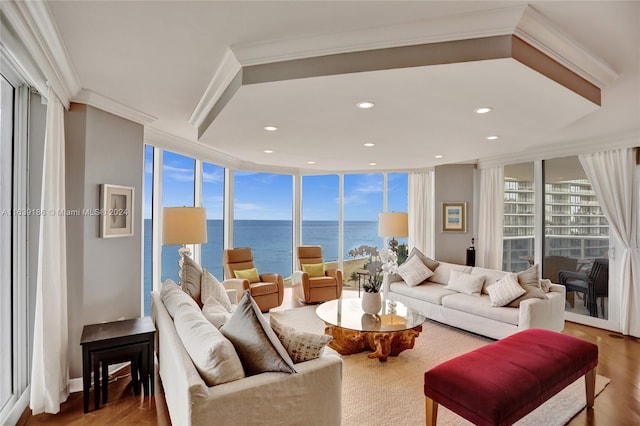 living room with a water view, a wall of windows, hardwood / wood-style flooring, and plenty of natural light