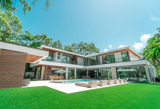 back of house with a balcony, a yard, a patio, and pool water feature