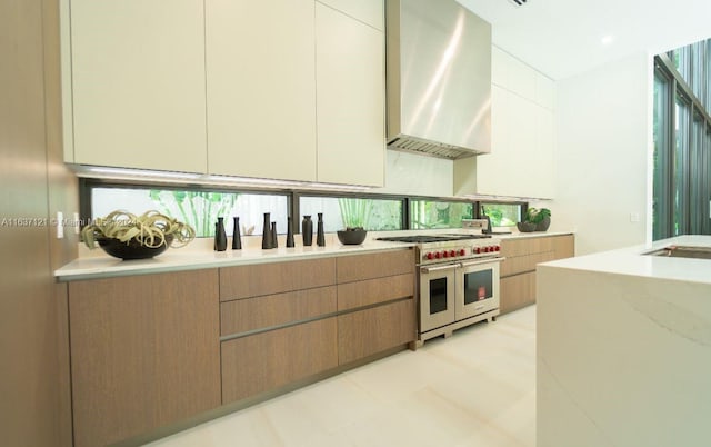 kitchen featuring a healthy amount of sunlight, range with two ovens, and wall chimney range hood