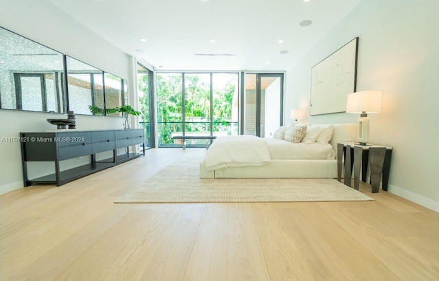 bedroom with light hardwood / wood-style floors, a wall of windows, and access to exterior