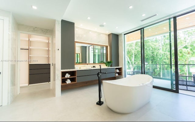 bathroom with expansive windows, vanity, and a washtub