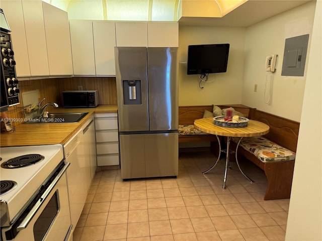 kitchen featuring breakfast area, sink, stainless steel fridge with ice dispenser, electric panel, and white cabinetry