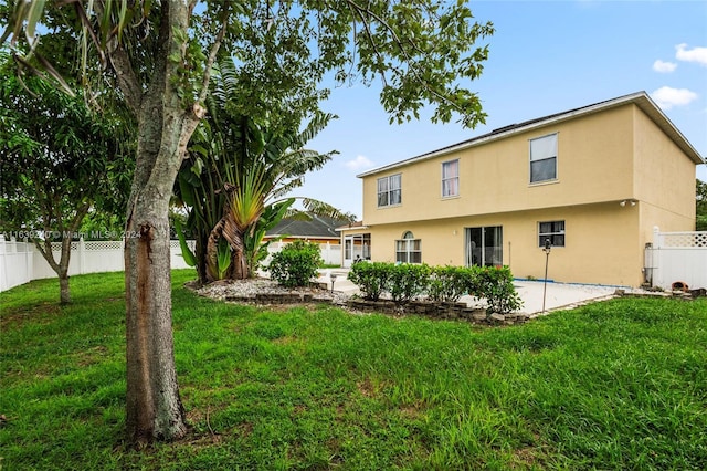 rear view of house featuring a yard, a patio, fence, and stucco siding