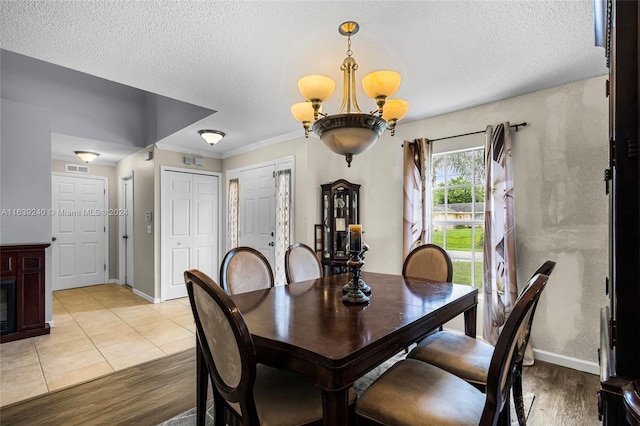 dining room with light wood finished floors, baseboards, a chandelier, and a textured ceiling