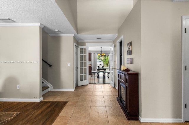 hall featuring light tile patterned floors, visible vents, baseboards, stairs, and ornamental molding