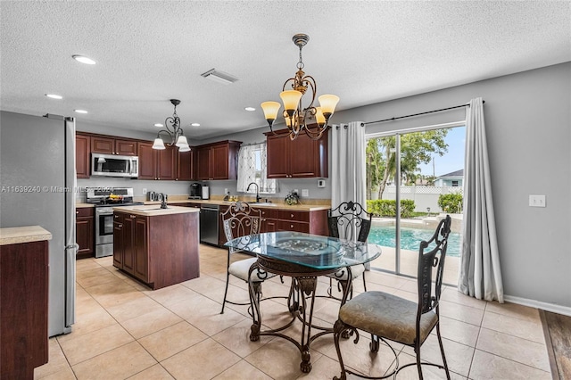 kitchen with a center island, stainless steel appliances, light countertops, visible vents, and a sink