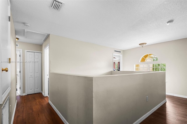 hallway with visible vents, an upstairs landing, and wood finished floors