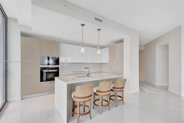 kitchen with hanging light fixtures, an island with sink, a breakfast bar, sink, and oven