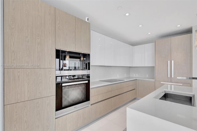 kitchen featuring light tile patterned flooring, black electric cooktop, sink, and light brown cabinets