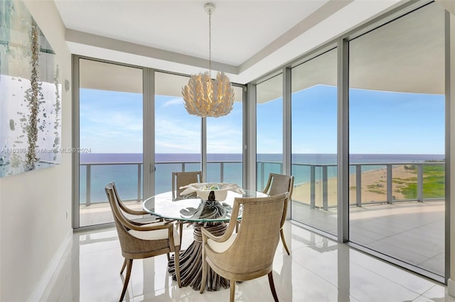 tiled dining room featuring a notable chandelier, a water view, and plenty of natural light