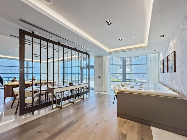 bedroom featuring a tray ceiling, expansive windows, and light hardwood / wood-style floors