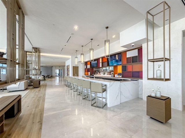 kitchen featuring light tile patterned flooring, pendant lighting, a kitchen bar, and kitchen peninsula