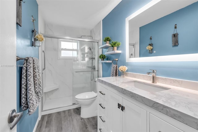 bathroom with hardwood / wood-style floors, vanity, toilet, and a shower with door