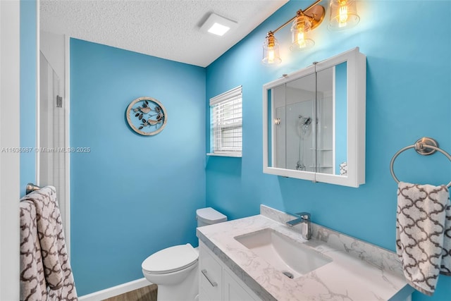 bathroom featuring vanity, a shower, a textured ceiling, and toilet