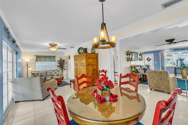 tiled dining room featuring ceiling fan with notable chandelier and ornamental molding