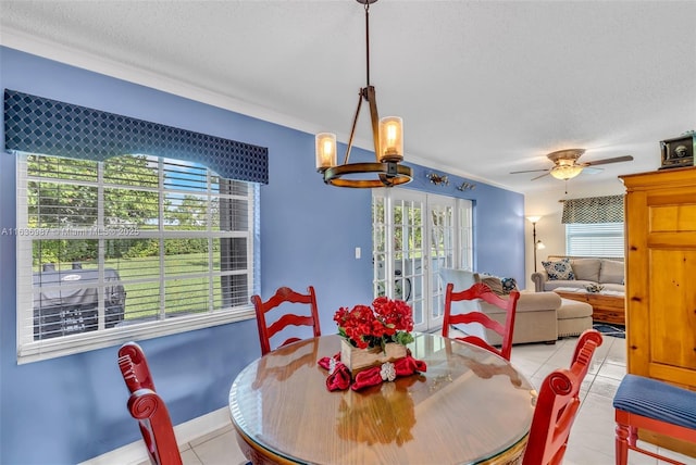 tiled dining room with a textured ceiling, plenty of natural light, ceiling fan with notable chandelier, and ornamental molding