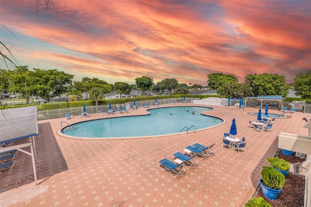 pool at dusk featuring a patio area and central AC