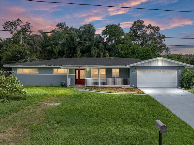 single story home featuring a garage, a lawn, and a porch