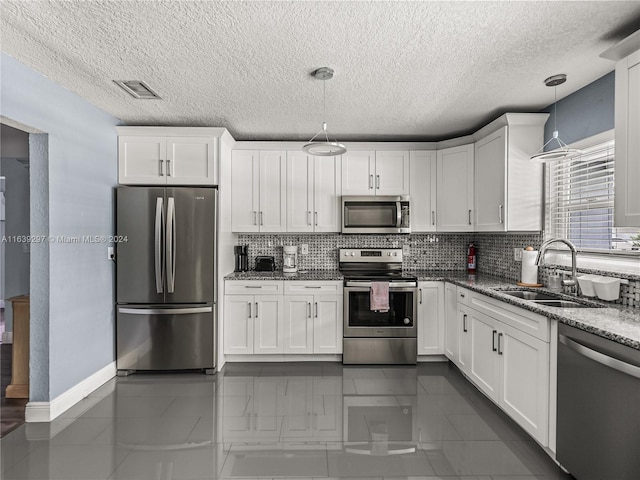 kitchen featuring stainless steel appliances, backsplash, light stone countertops, white cabinets, and sink