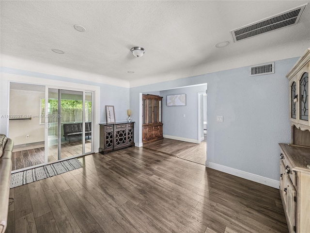 unfurnished living room featuring a textured ceiling and dark hardwood / wood-style flooring