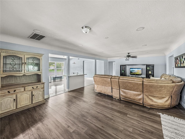 living room featuring ceiling fan, dark hardwood / wood-style flooring, and a textured ceiling